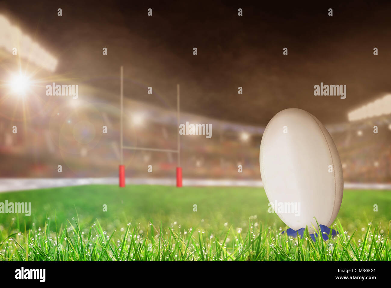 White rugby ball on a kicking tee on the grass ready for conversion or penalty kick toward goal post. Deliberate shallow depth of field on brightly li Stock Photo