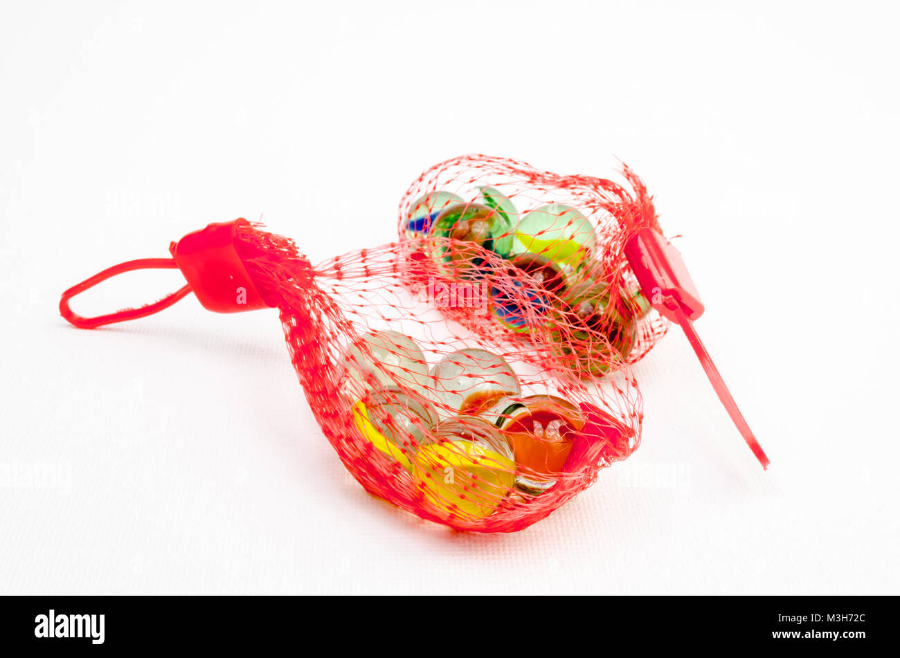A Studio Photograph of Two Red Mesh Bags containing Glass Marbles Stock Photo