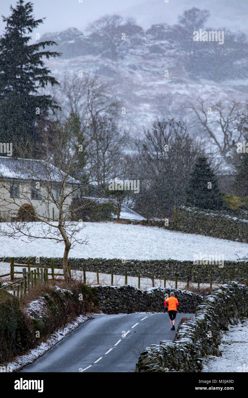 Lake District, Cumbria, 11th February 2018. UK Weather. A yellow warning for snow in the area from the Met Office for today with snow fall already in the village of Troutbeck and the Kirkstone Pass, Cumbria, England. An early morning run up the Kirkstone Pass for this runner as snow begins to fall near to the village of Troutbeck, Cumbria Stock Photo