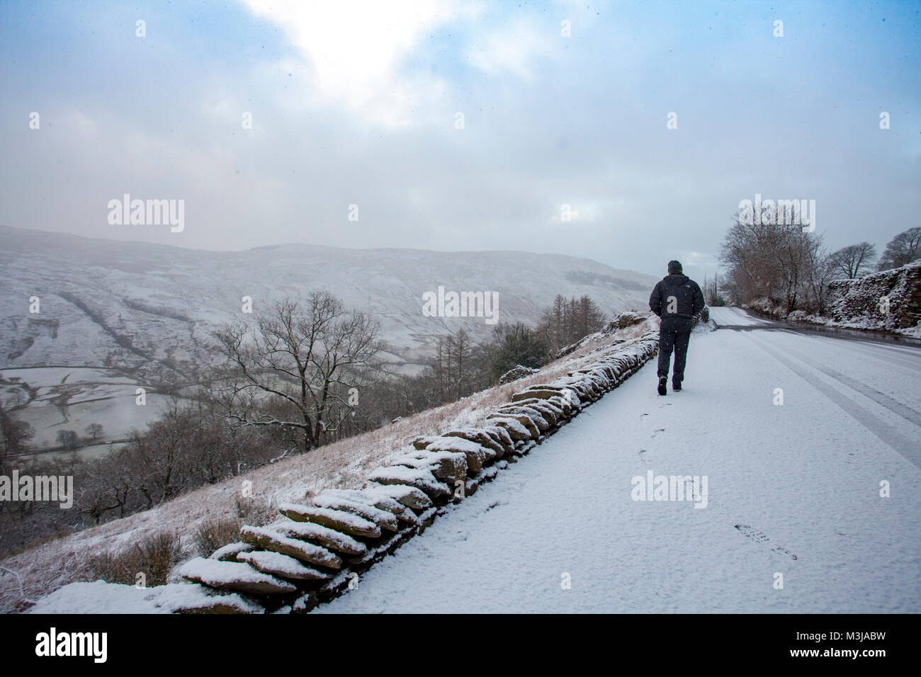 Lake District, Cumbria, 11th February 2018. UK Weather. A yellow warning for snow in the area from the Met Office for today with snow fall already in the village of Troutbeck and the Kirkstone Pass, Cumbria. A person walking down the Kirkstone Pass in wintry conditions near to the village of Troutbeck, Cumbria Stock Photo