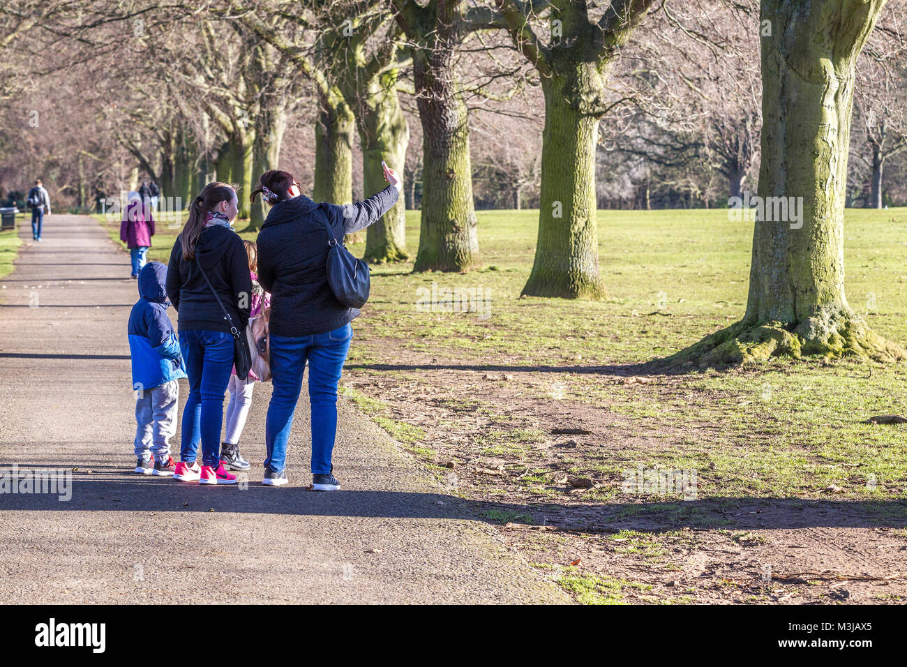 Northampton, U.K. Weather. 11th February 2018. Weather. A very cold sunny morning in Abington Park,  a family heads down towards the lake wrapped up warm to feed  the Black-headed Gulls and pigeons. Credit: Keith J Smith./Alamy Live News Stock Photo