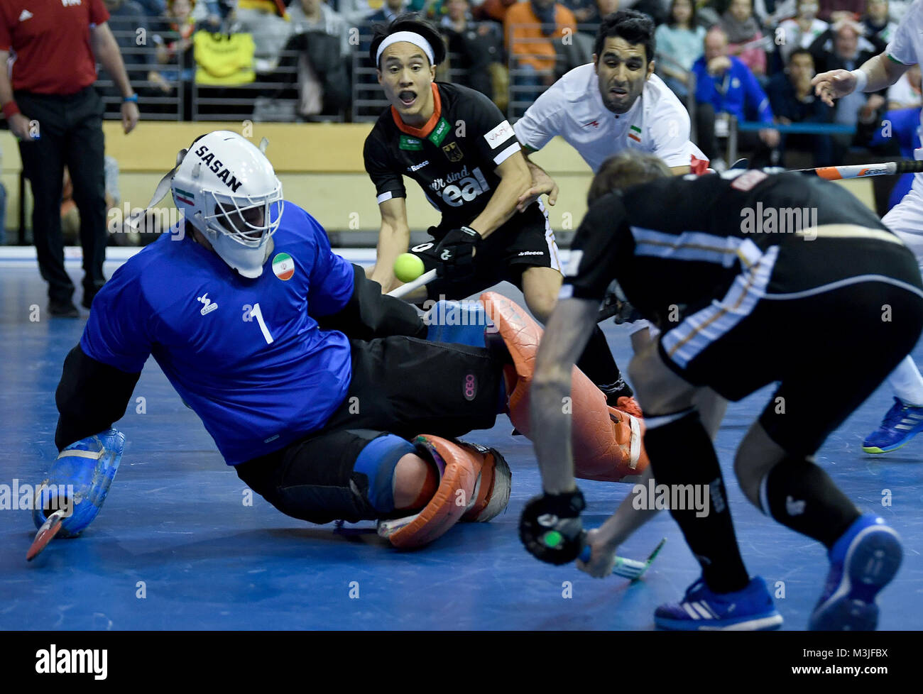 Iran's goalkeeper Sasan Hatami Nejad (L) defends his goal against Dan Nguyen (C) and Marco Miltkau (R) of Germany during the men's Indoor Hockey World Cup 2018 semifinals match between Germany and the Iran at the Max-Schmeling Halle in Berlin, Germany, 10 Febuary 2018. Photo: Britta Pedersen/dpa Stock Photo