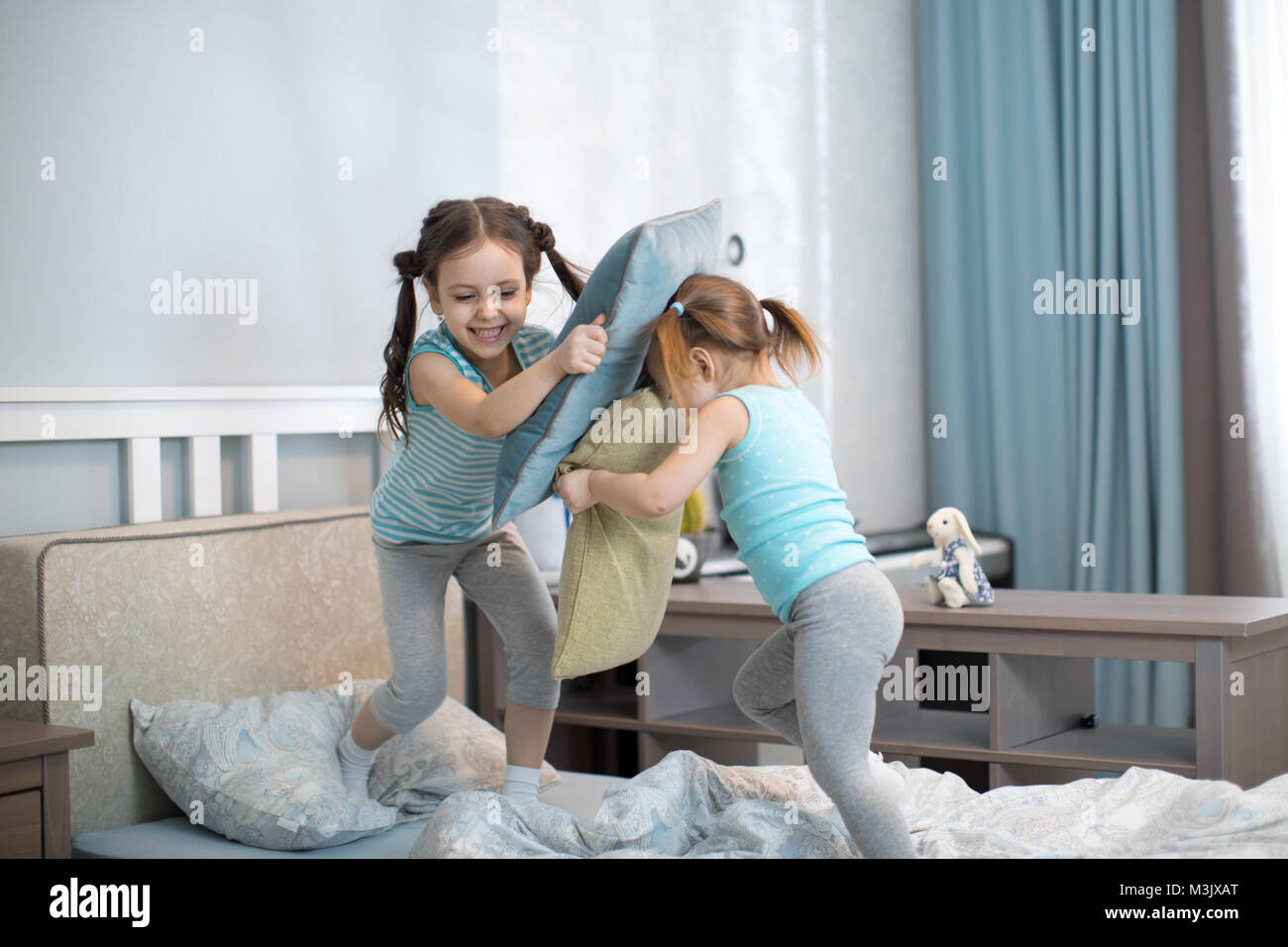 kids girls have fun playing with pillows at home Stock Photo