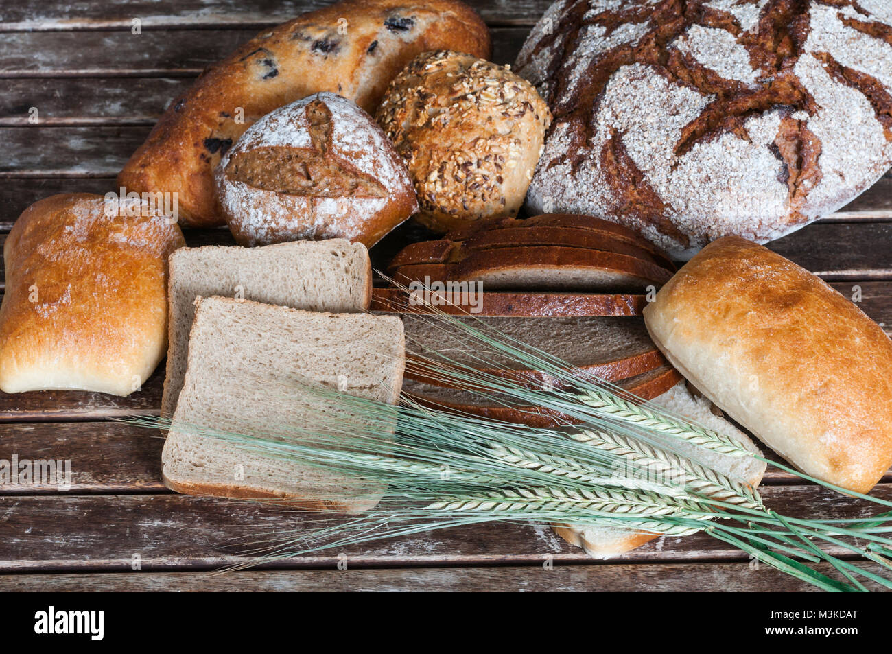 Verschiedene Brotsorten mit Getreideaehren auf einem Holztisch. Stock Photo