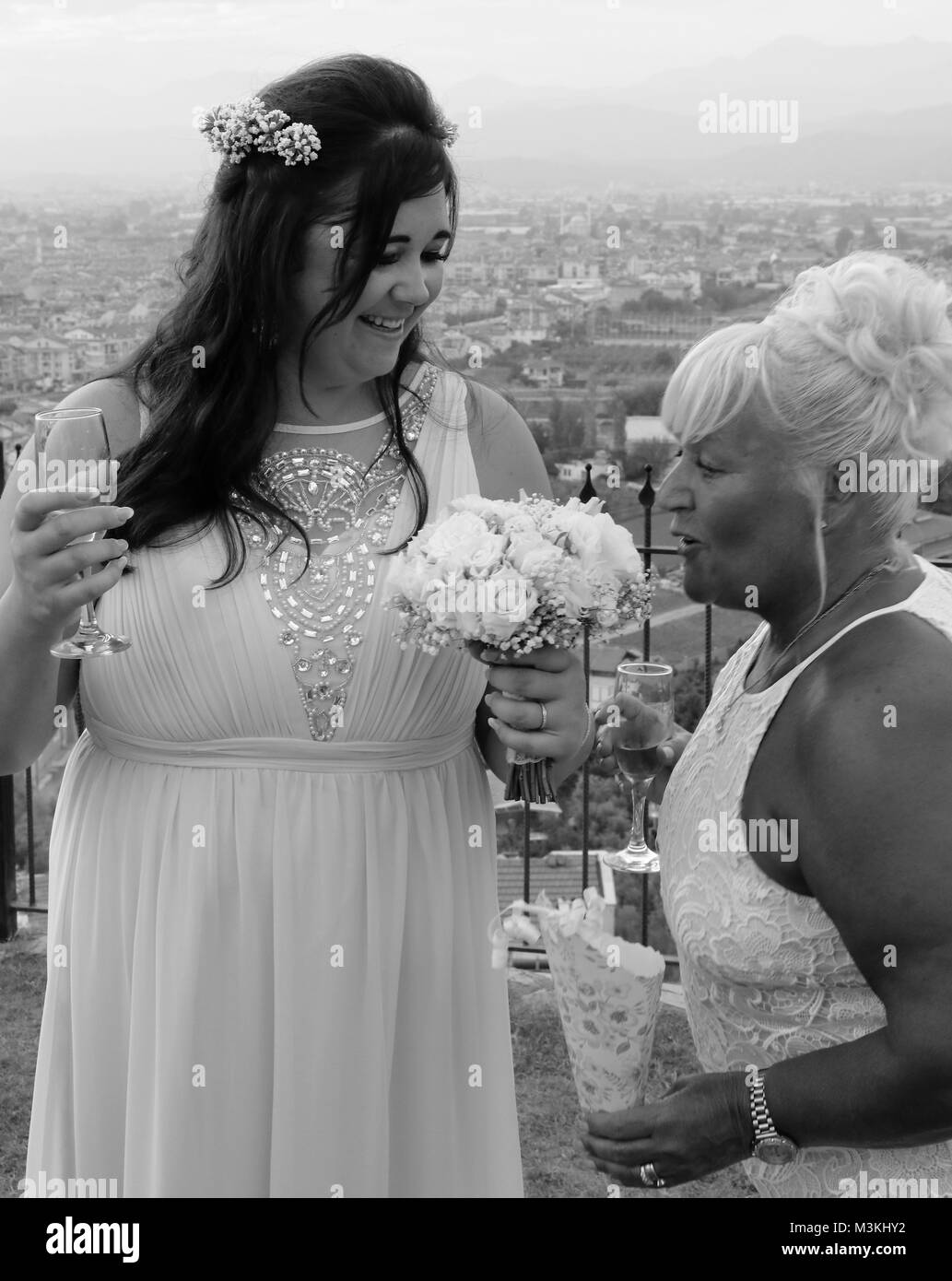 4TH AUGUST 2017, TURKEY: A bride with a  wedding guest smelling the bouquet of flowers at her wedding in turkey, 4th august 2018 Stock Photo