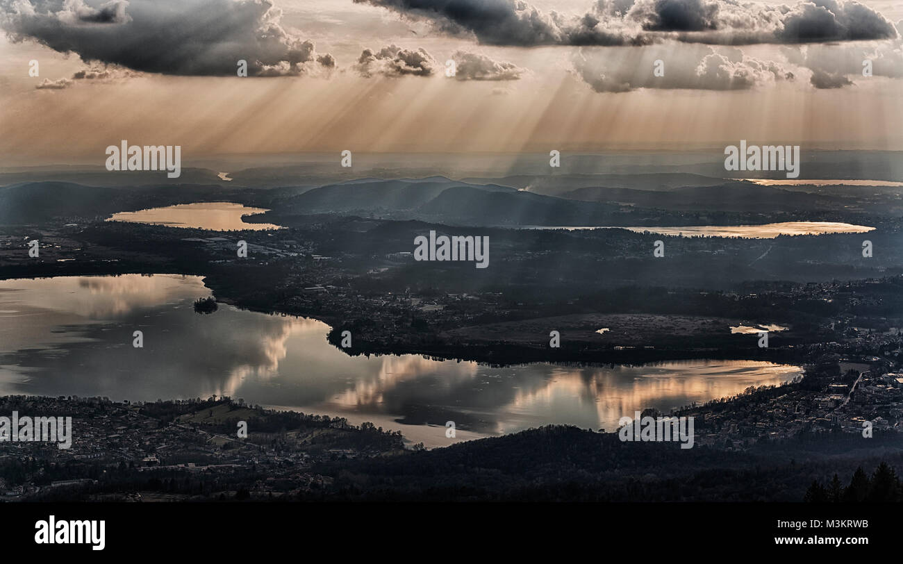 rays of sun in the clouds above the lakes of the province of Varese in winter season Stock Photo