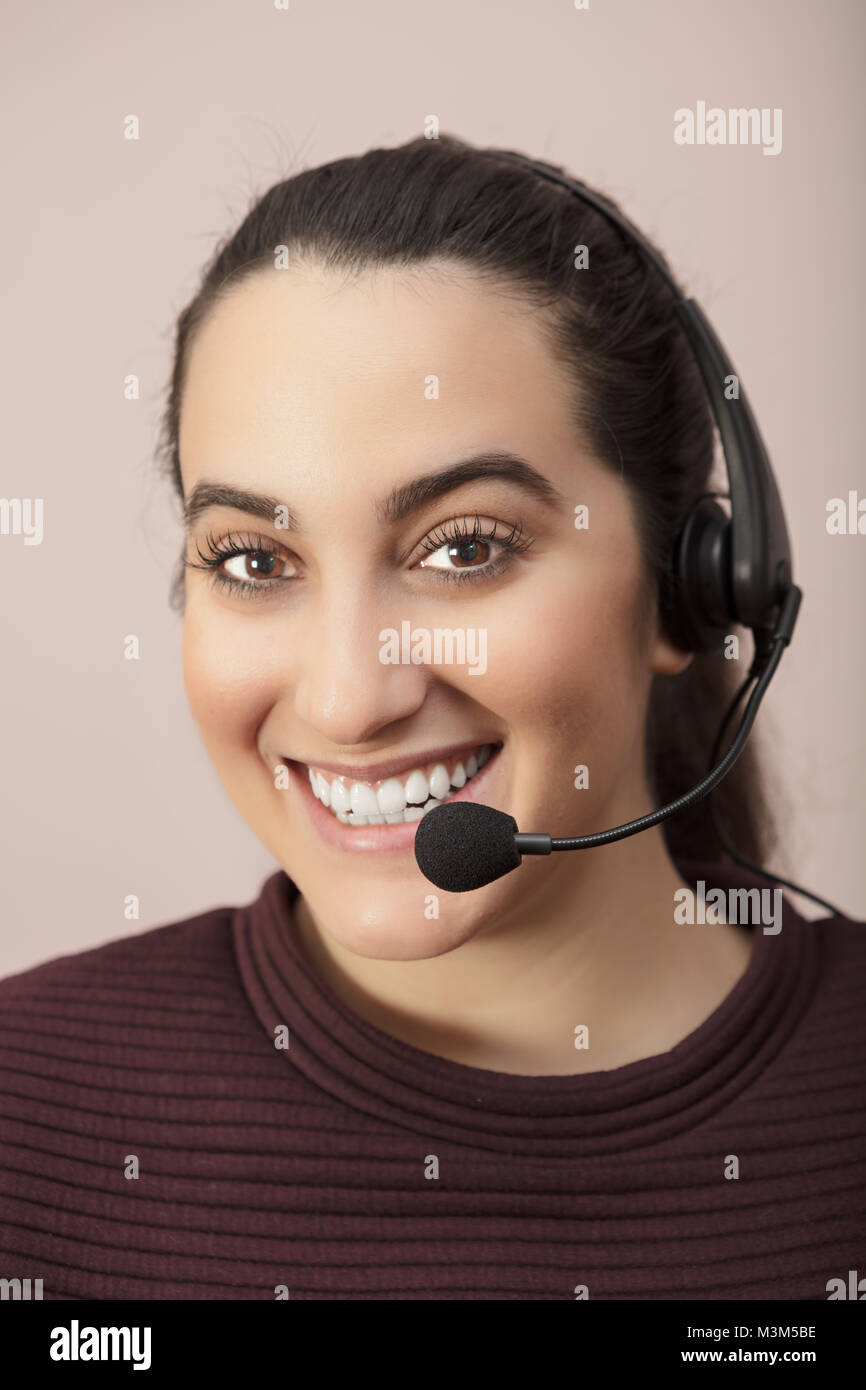 Happy smiling attractive young woman wearing a headset in a concept of a call center operator, customer service or telesales saleslady Stock Photo