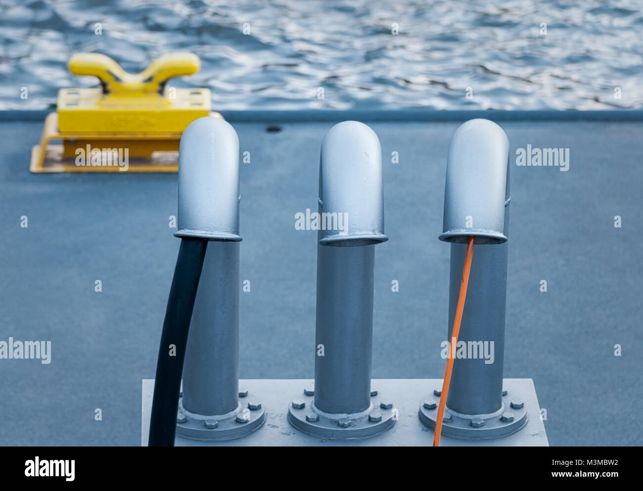 Yellow bollard and three cable funnels in the port of Hamburg at daylight, selective focus. Stock Photo