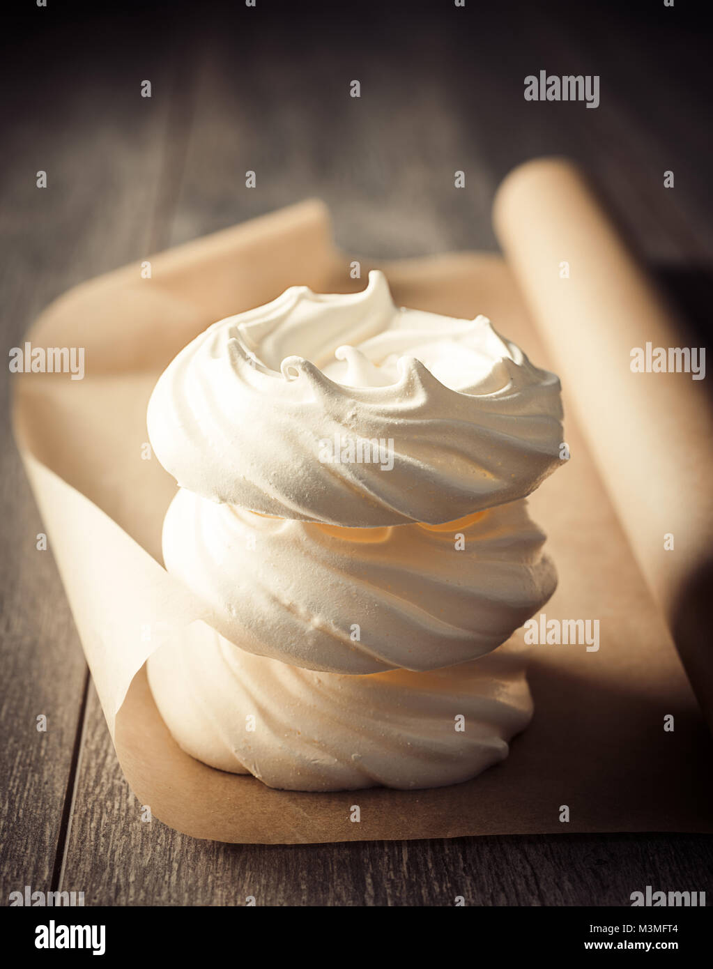 Stack of three meringue nests on parchment paper fresh out of the oven