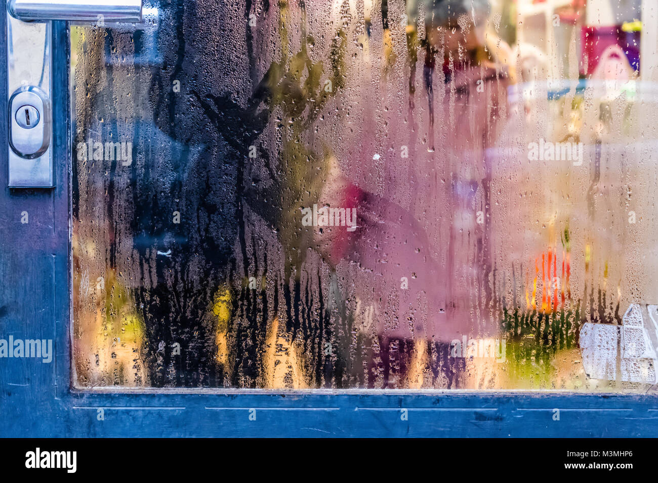 Blue Iron Door. Fogged glass with drops of water from the rain