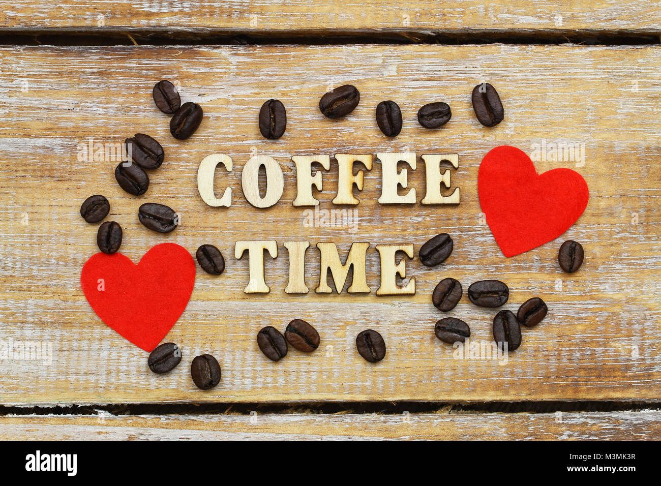 Coffee time written with wooden letters on rustic surface, two red hearts and coffee beans Stock Photo