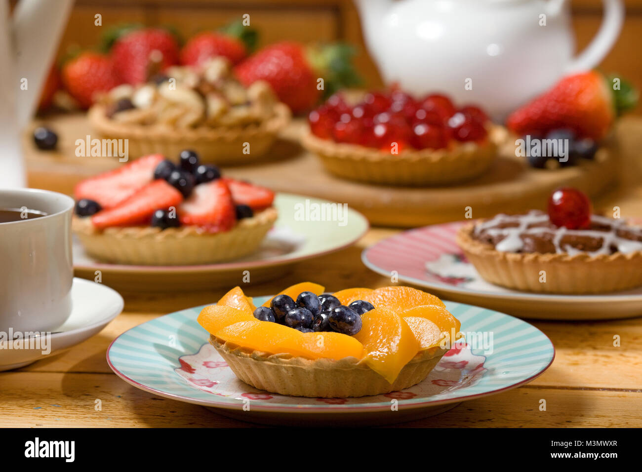 Peach and blueberry tart with a selection of tarts in the background Stock Photo