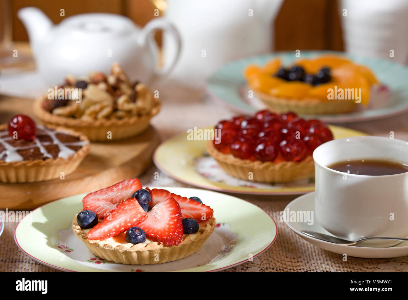 A selection of fruit tarts with strawberry and blueberry tart in the foreground Stock Photo