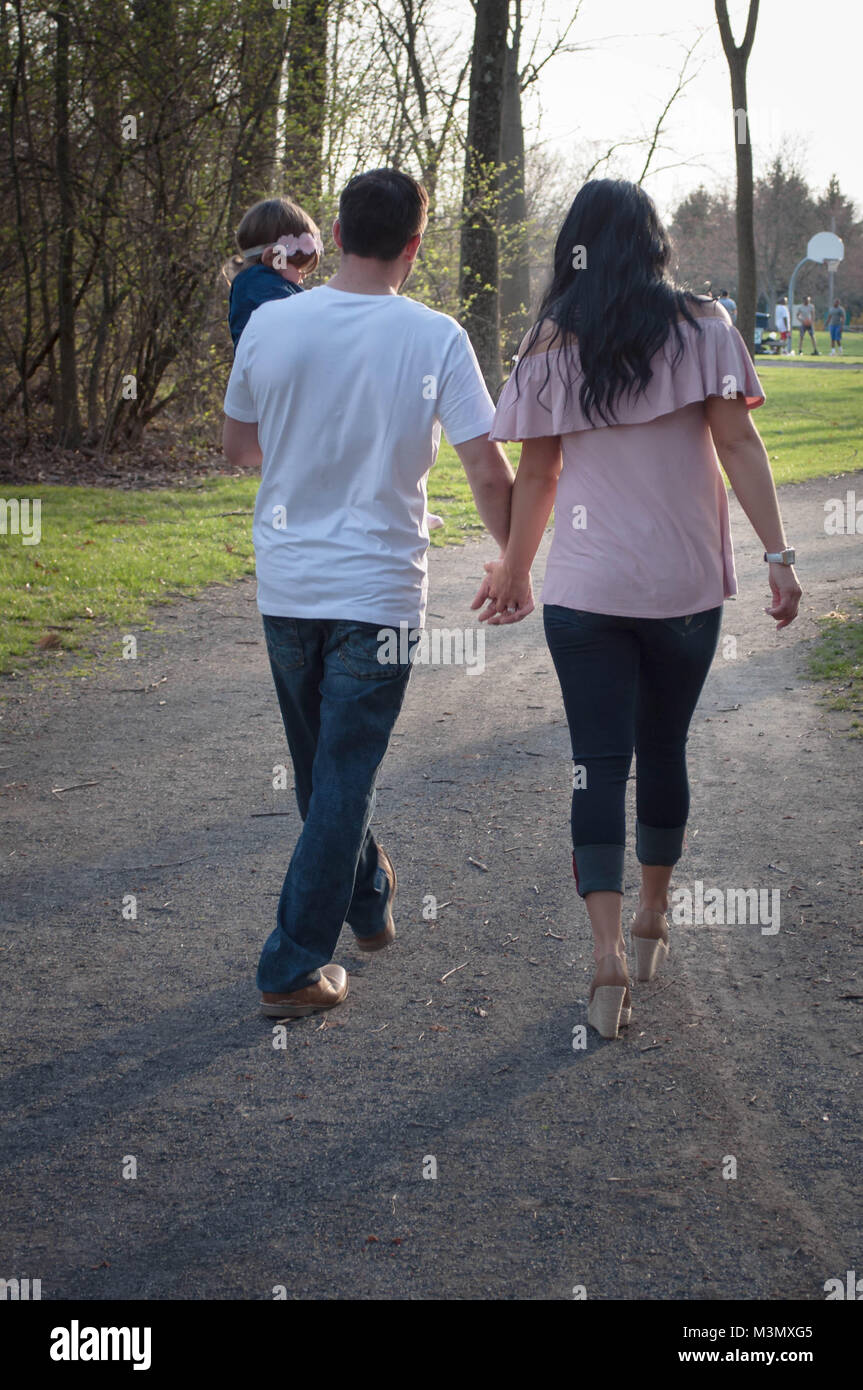 Parents Holding Hands and Child While Walking Through a Park Stock ...