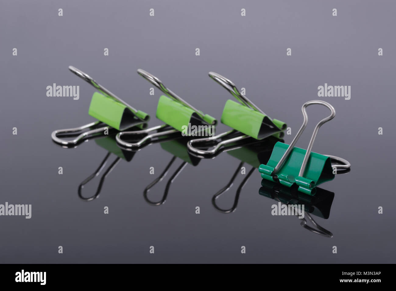 Macro photo of green paper clips on a reflective surface Stock Photo