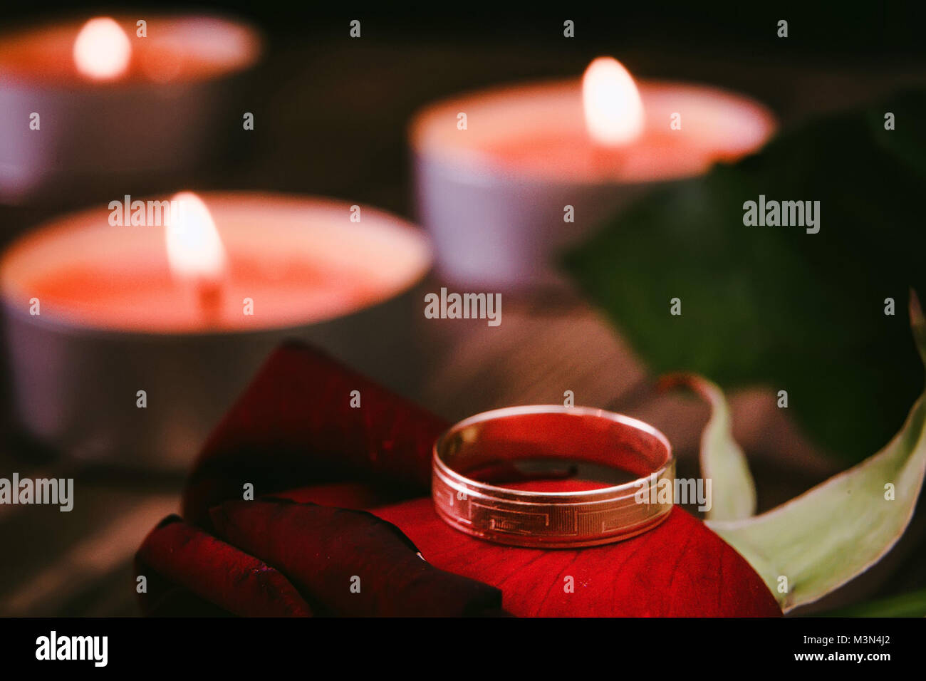 Wedding ring on rose petal and candles background Stock Photo Alamy