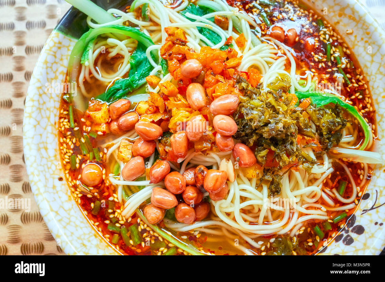 Spicy noodle soup with vegetables, herbs, peanuts and coriander, popular in Yunnan Province, shallow depth of field, China. Stock Photo