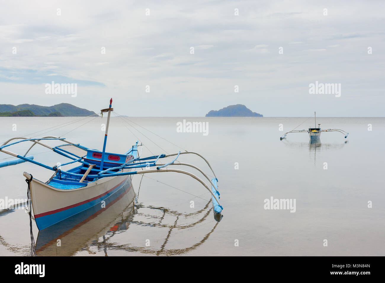 Filipino fisherman boats with traditional outriggers float anchored in ...