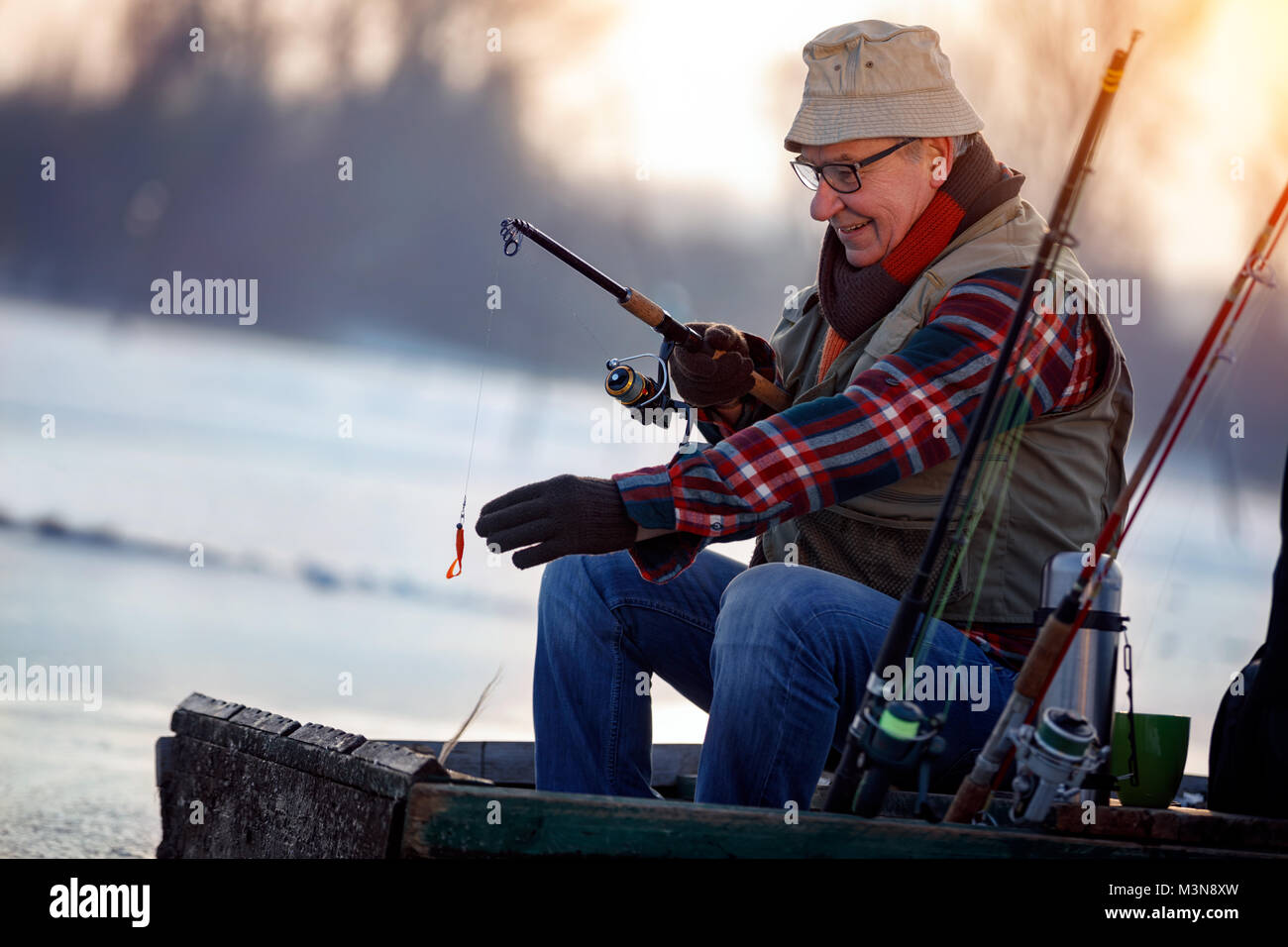 Winter hobby -elderly man fishing on lake Stock Photo
