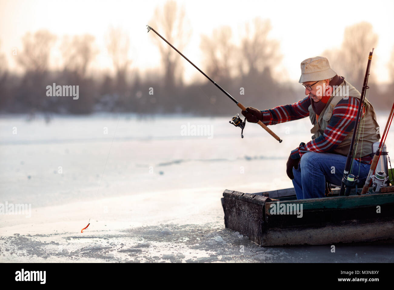 elderly man fishing in the winter on the frozen lake Stock Photo