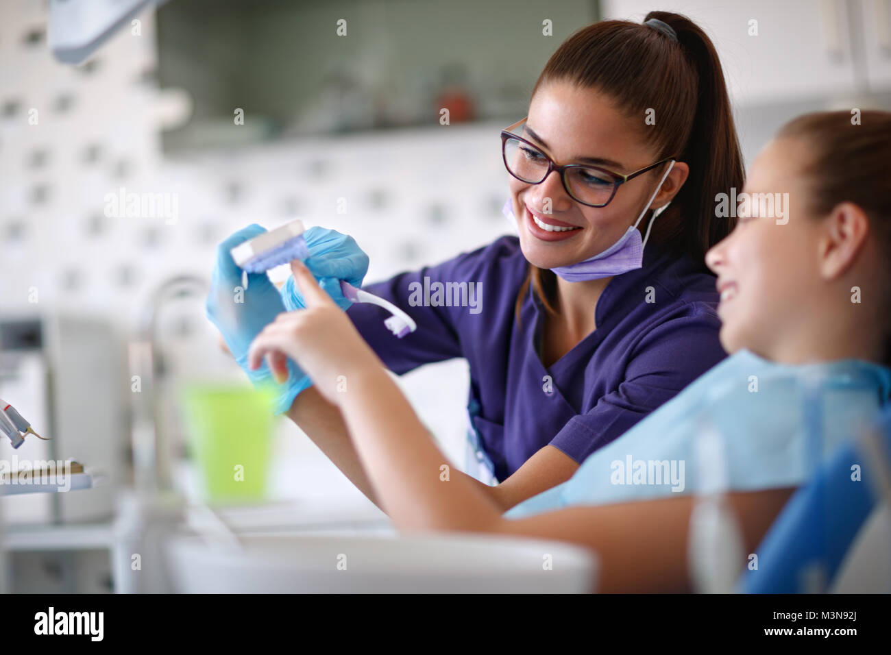 Female dentist educates little girl how to brush teeth Stock Photo