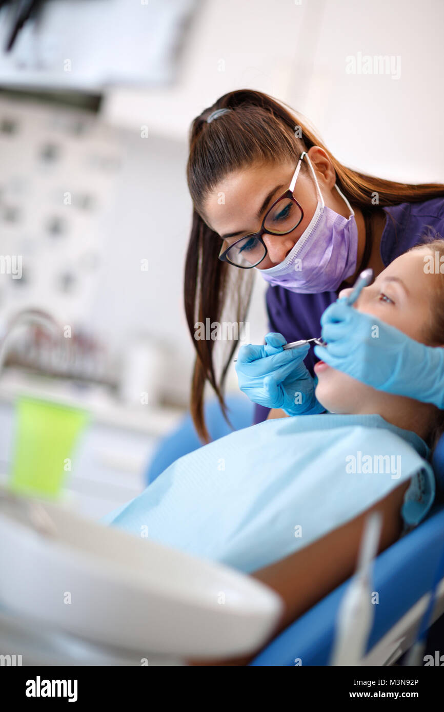 Female dentist repairing tooth to female patient in dental chair Stock Photo