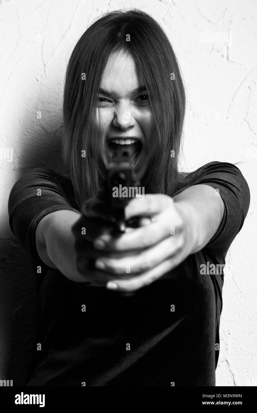 fun girl with gun on white background aiming at camera, screaming, monochrome Stock Photo