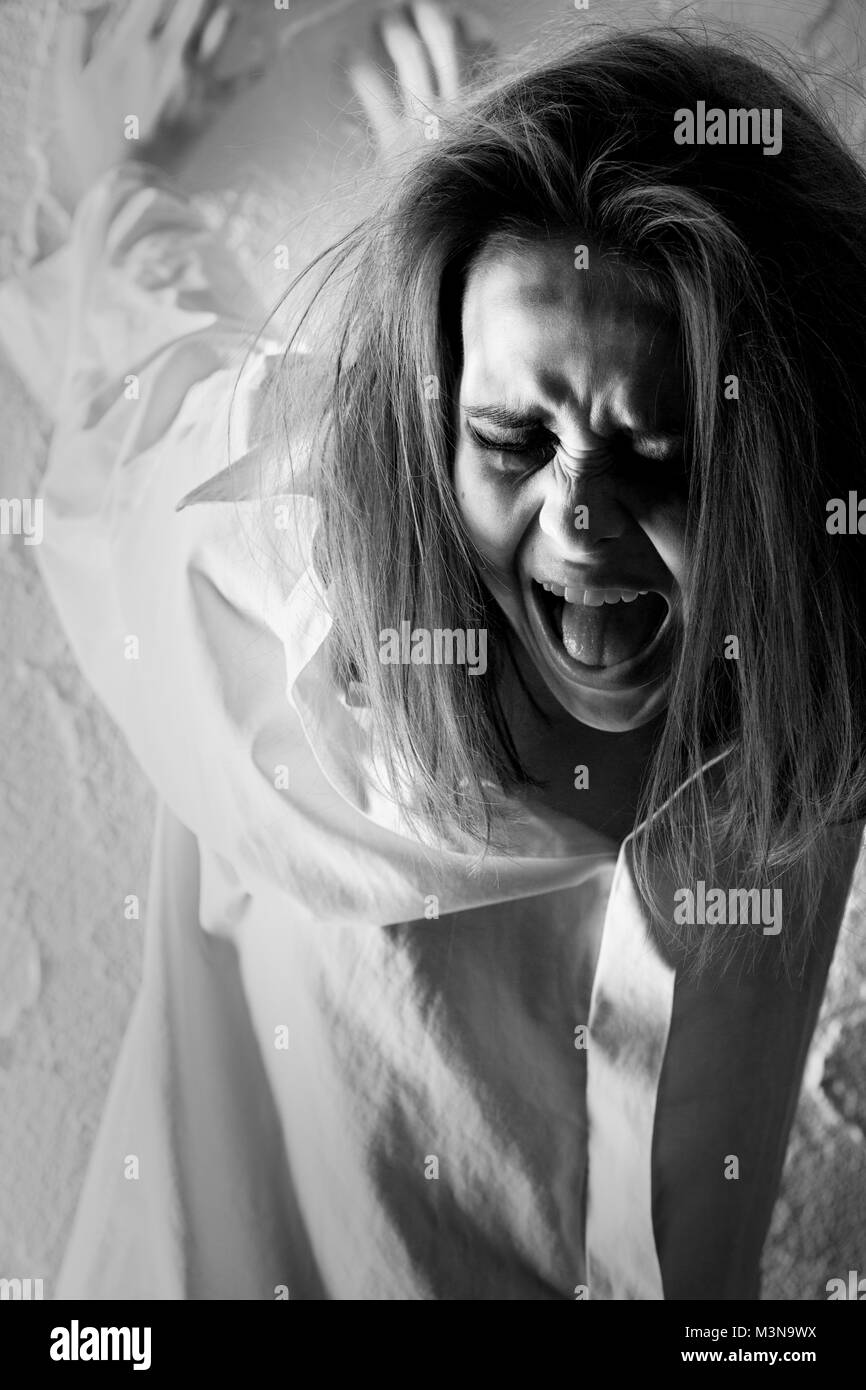 crazy woman with fluffy hair near wall screaming, monochrome Stock Photo