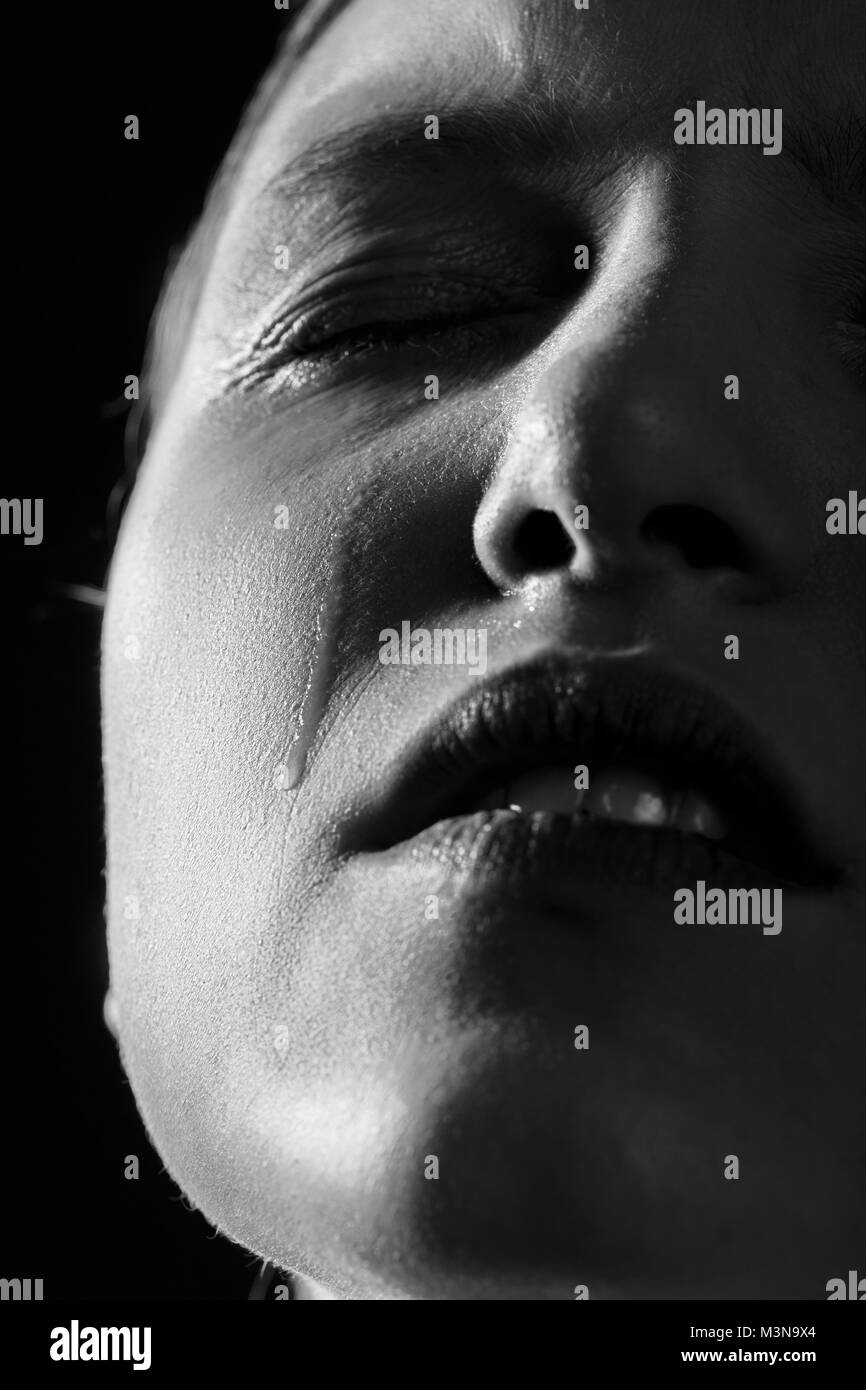 sad woman crying on black background, closeup portrait monochrome Stock Photo