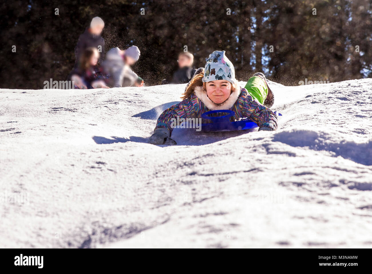 girl sledding down snowy hill on sled fast speed Stock Photo Alamy
