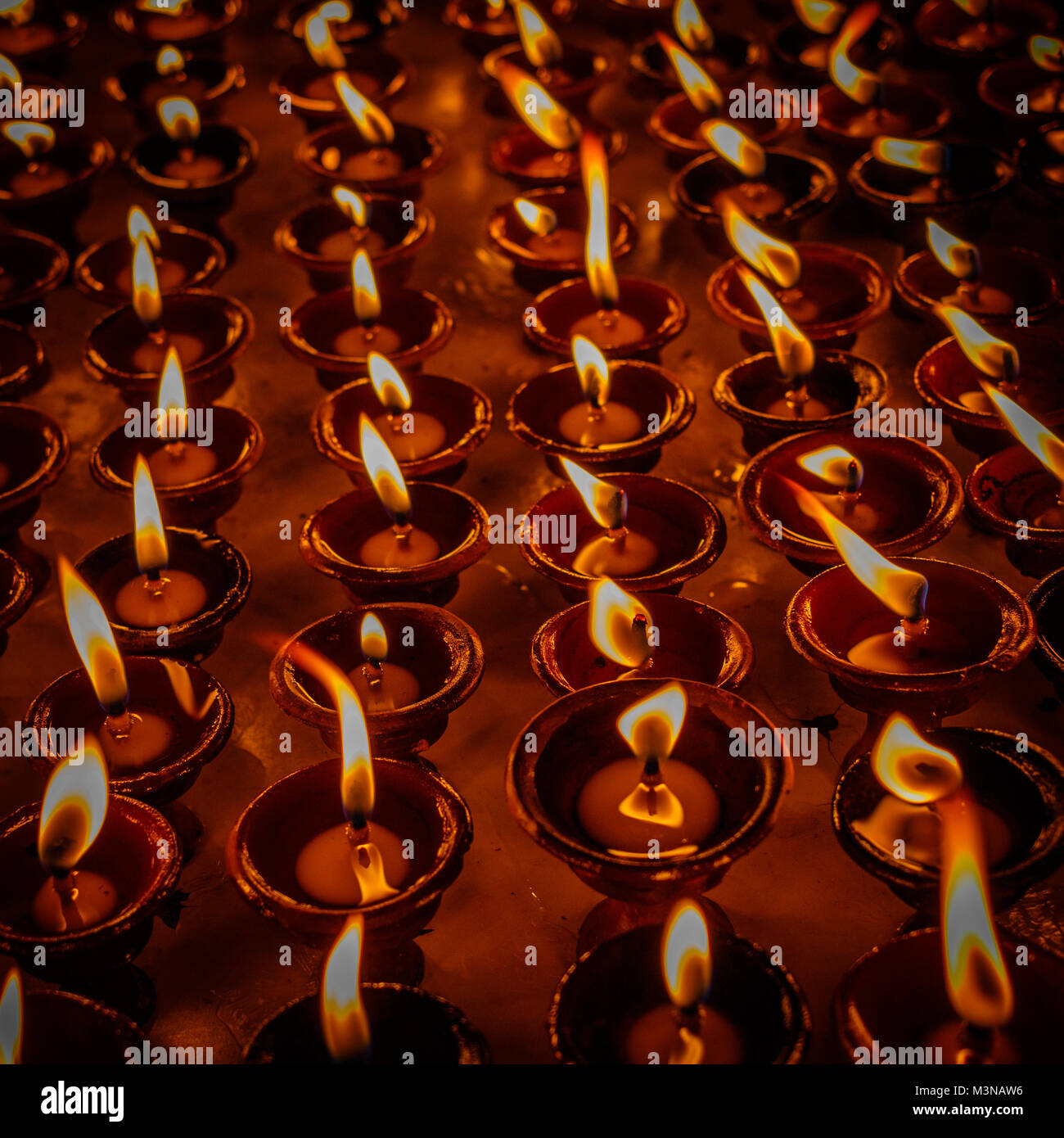 Oil lamps for the evening prayers burning at Boudhanath stupa, Kathmandu, Nepal. Square image. Stock Photo