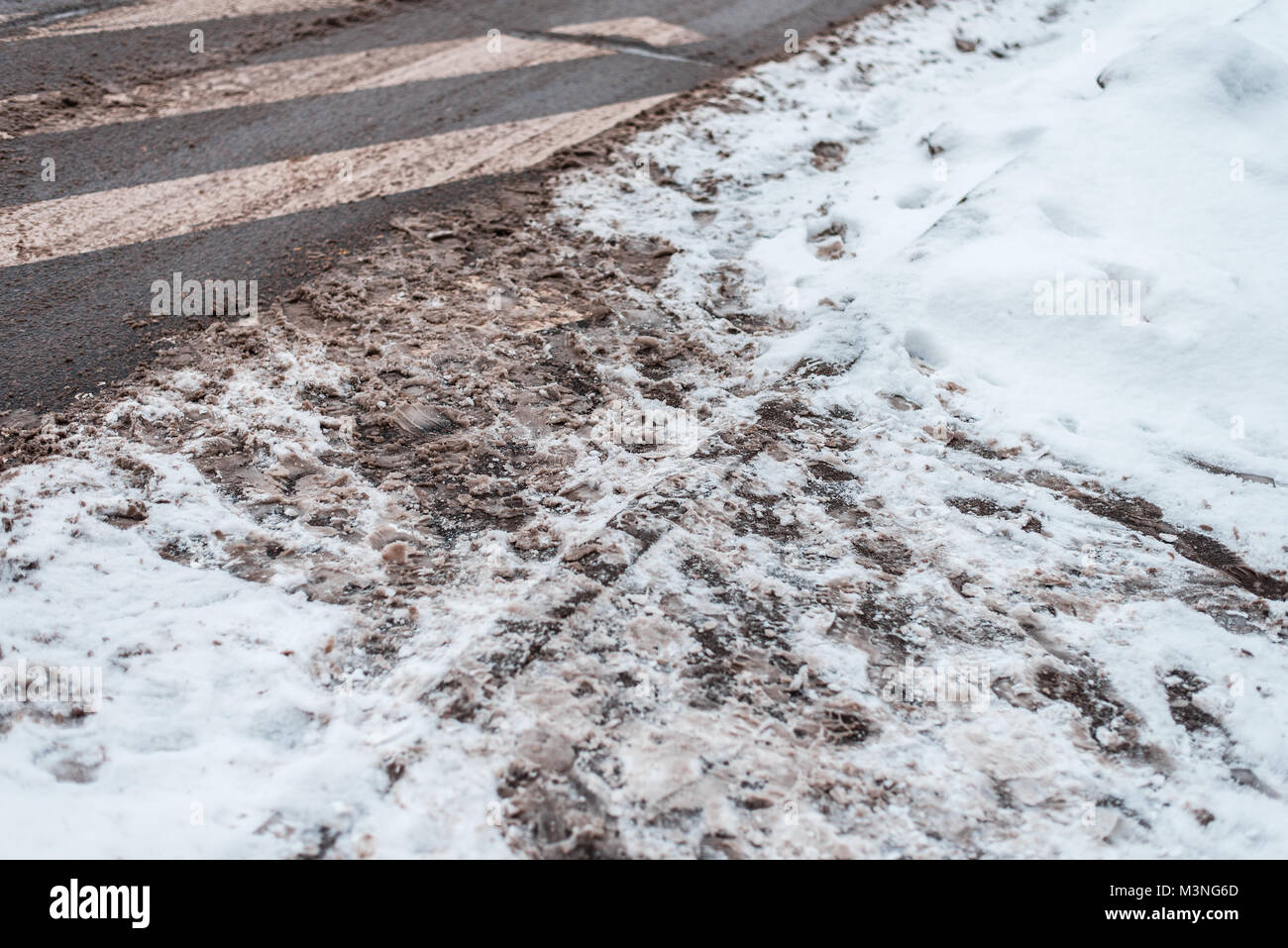 Winter in city of zebra pedestrian crossing. Dirty snow tracks auto car