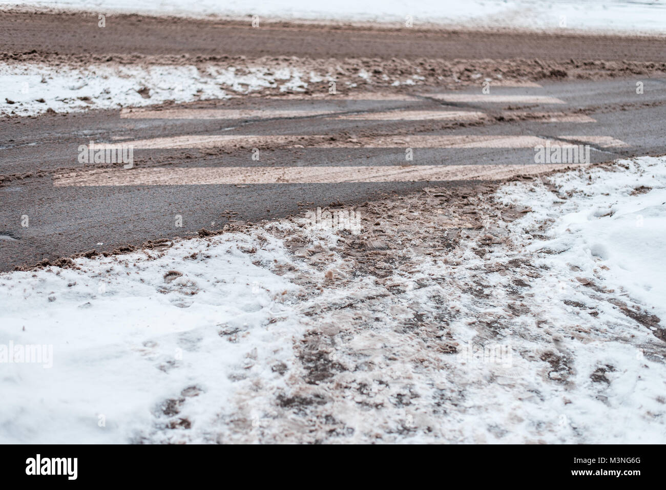 Winter in city of zebra pedestrian crossing. Dirty snow tracks auto car