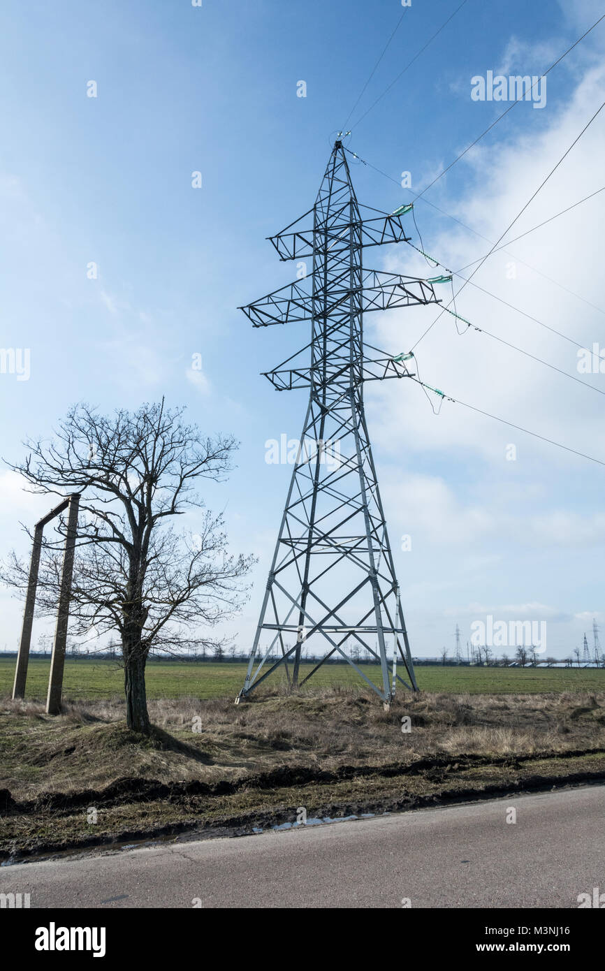 Power poles and high power lines in Ukraine and sky blue natural clouds in february Stock Photo