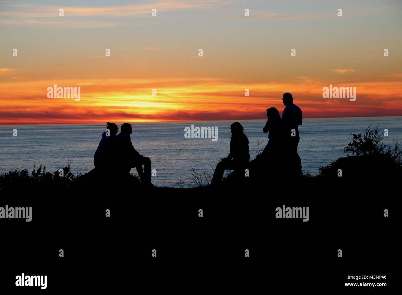 Friends enjoy the dramatic sunset over the Pacific Ocean, Big Sur, California. Stock Photo