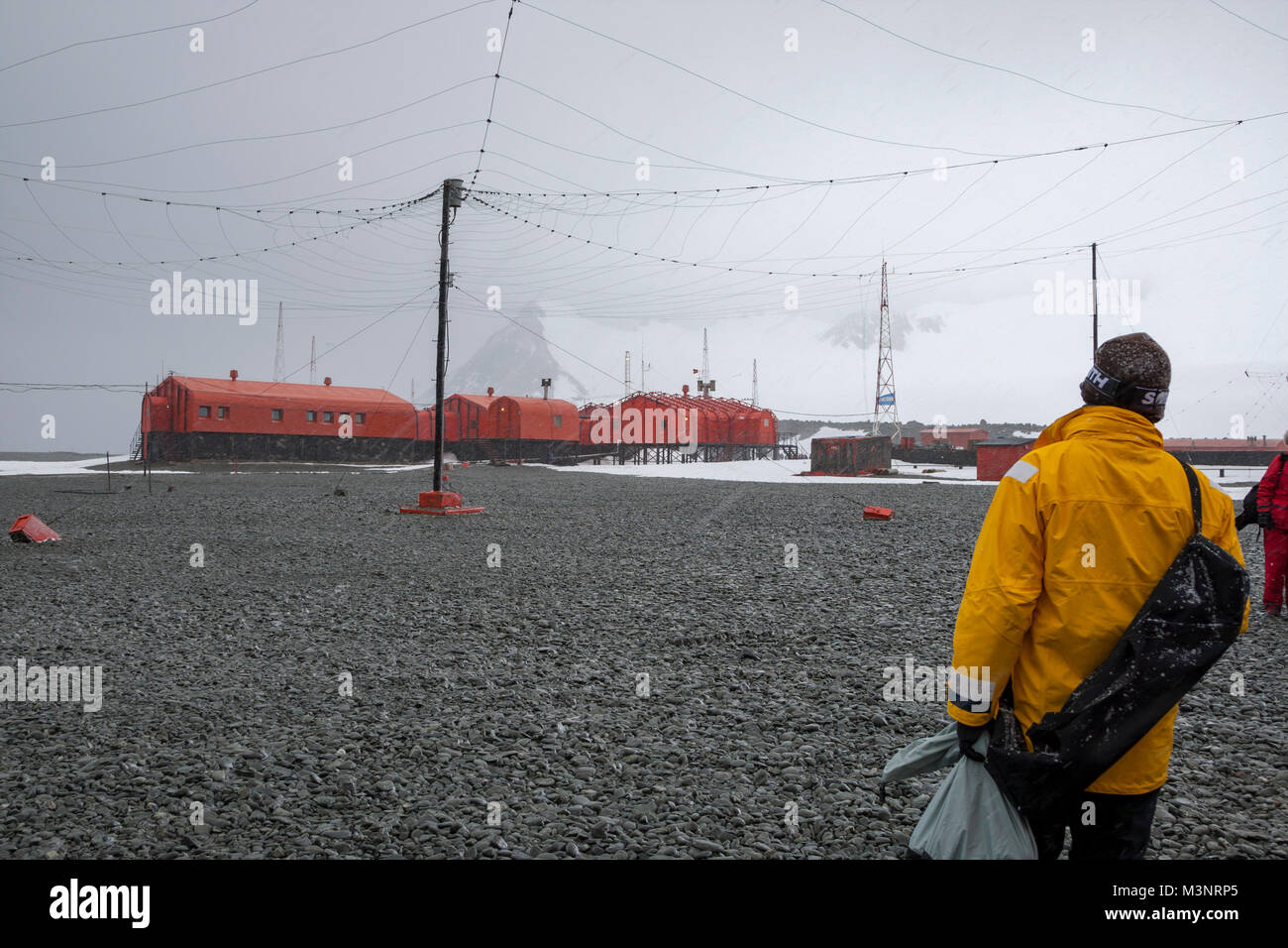Photographer walks toward Antarctic Naval Research base Antarctica , windy white out snow storm person looking at base Stock Photo