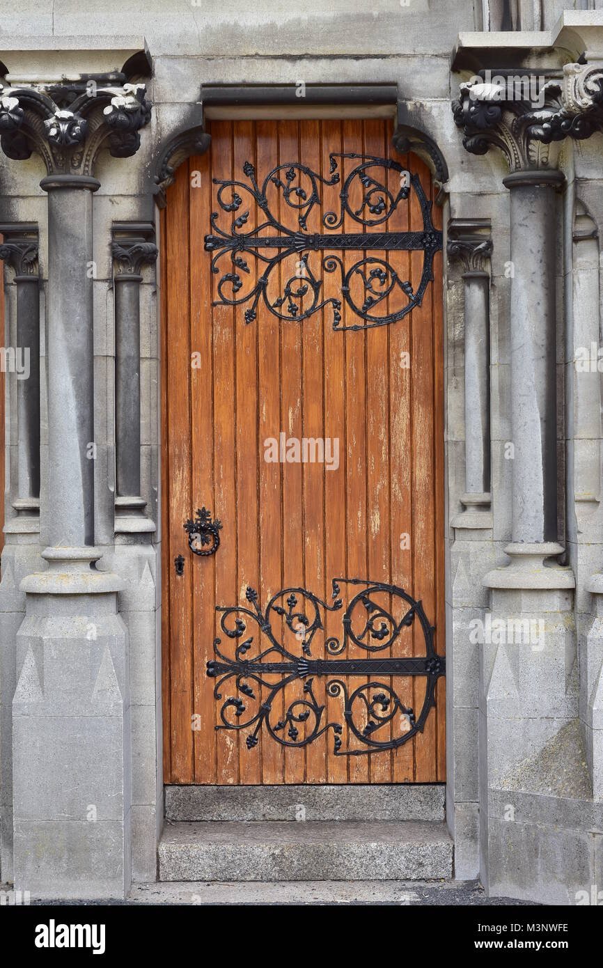Ancient wooden door with weathered paint and ornamental iron hinges in ...