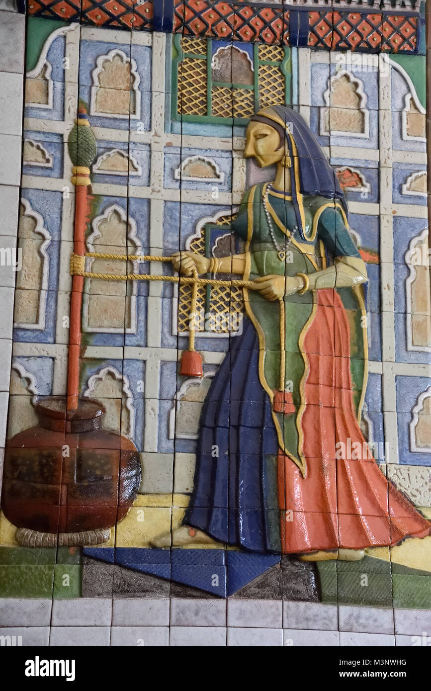 Lady churning butter milk on ceramic tiles at Chail Palace, Himachal Pradesh, India, Asia Stock Photo