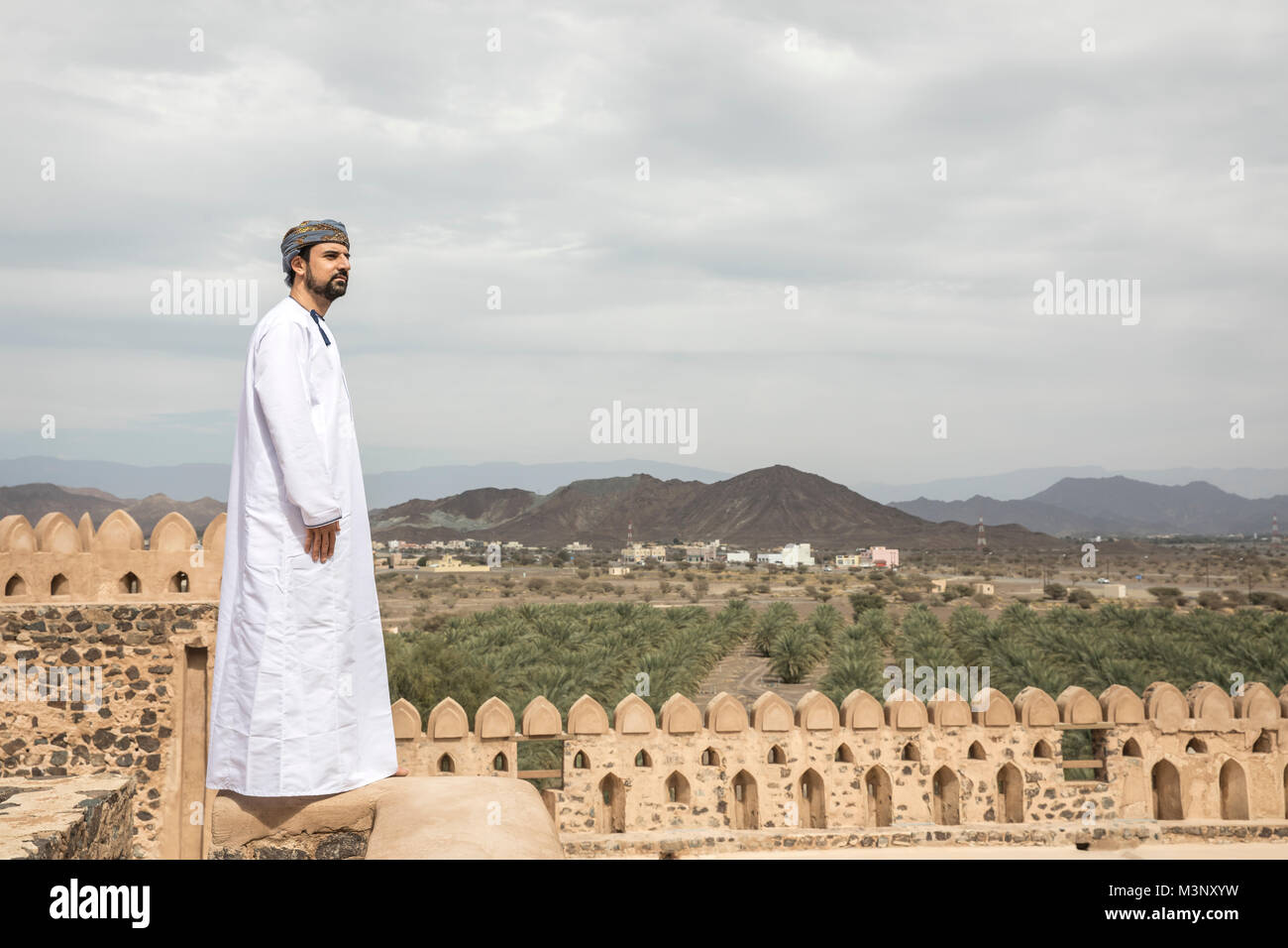 arab man in traditional omani outfit pointing to the distance Stock Photo
