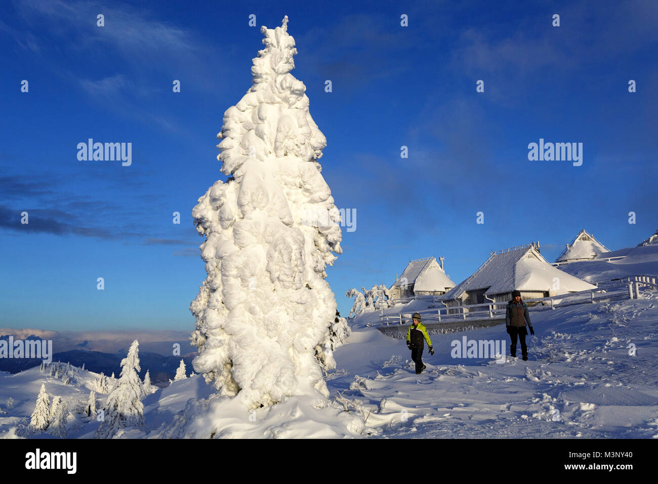 Mother And Son Hiking On Snow Covered Mountain With Frozen Cabins