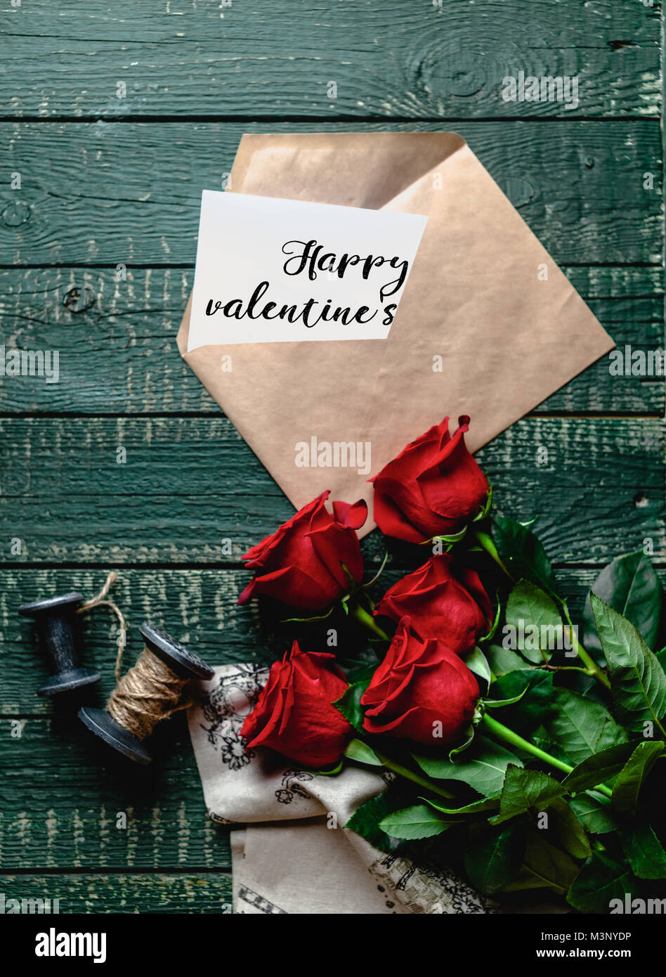 top view of red roses and envelope with Happy valentines day greeting ...