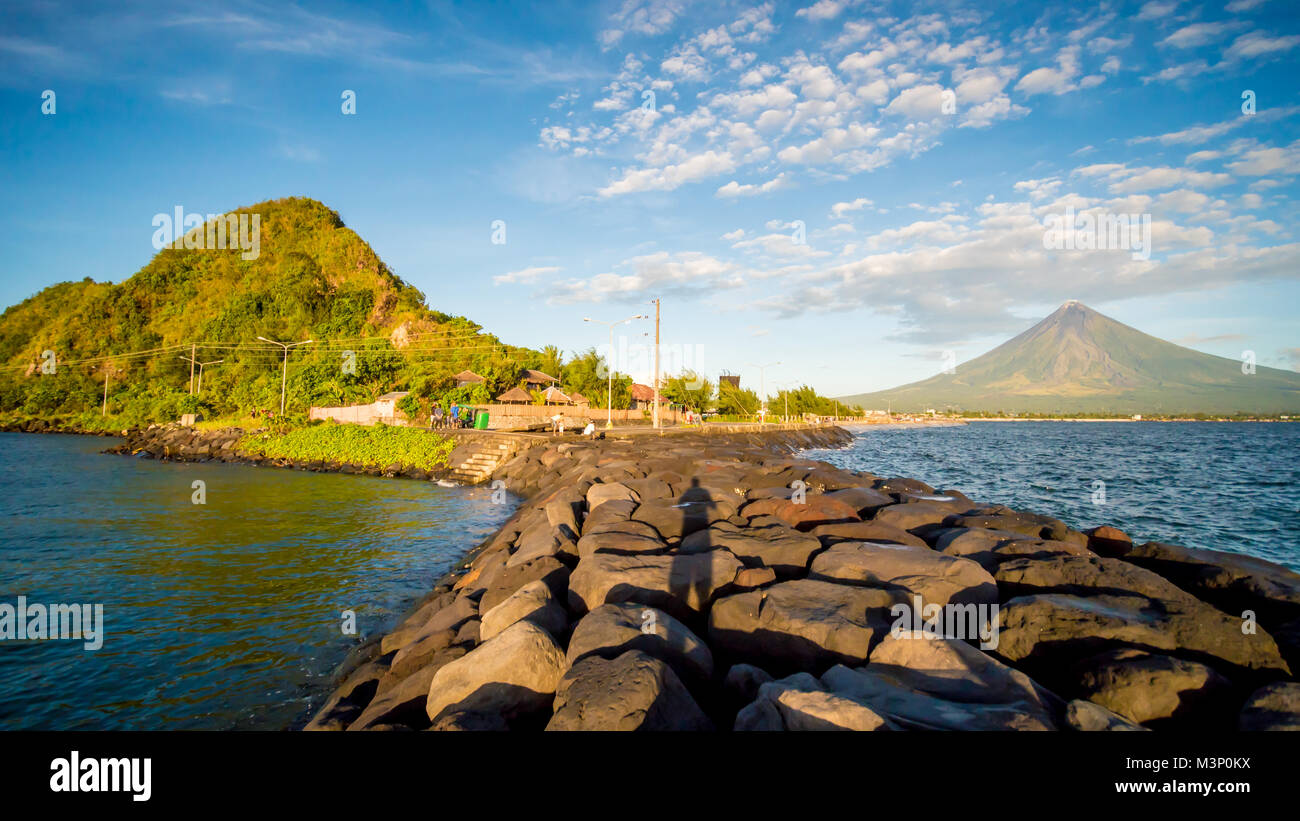 Legazpi City, Luzon, Philippines - Mount Mayon volcano looms over the city as daily life goes on. Stock Photo