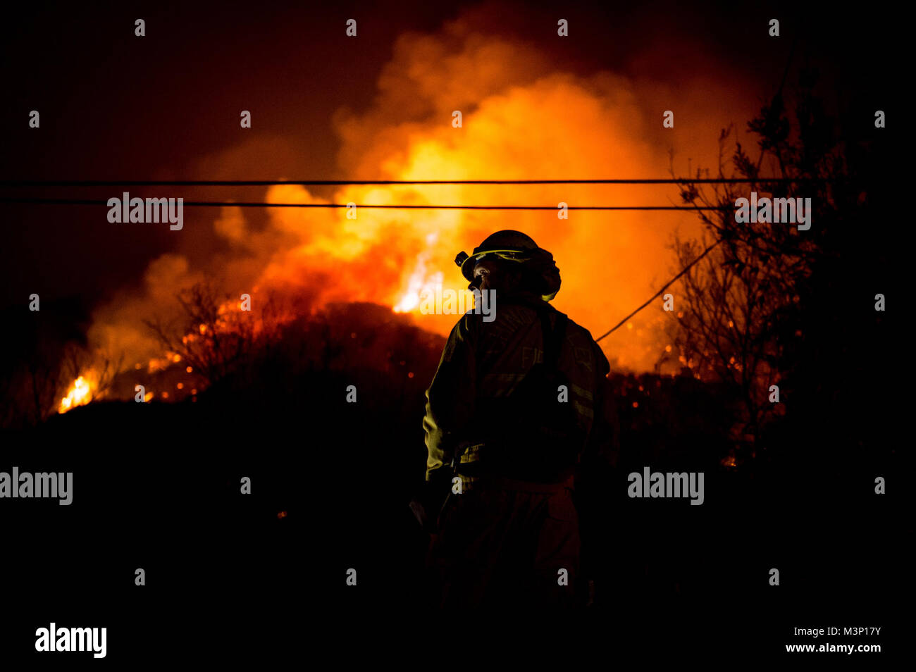 Chino Valley firefighters watch the oncoming flames of the Thomas Fire from the yard of a home in Montecito, California, Dec. 12, 2017. C-130Js of the 146th Airlift Wing at Channel Islands Air National Guard Base in Port Hueneme, carried the Modular Airborne Fire Fighting System and dropped fire suppression chemicals onto the fire's path to slow its advance in support of firefighters on the ground. (U.S. Air Force photo by J.M. Eddins Jr.) 171212-F-LW859-835 by AirmanMagazine Stock Photo