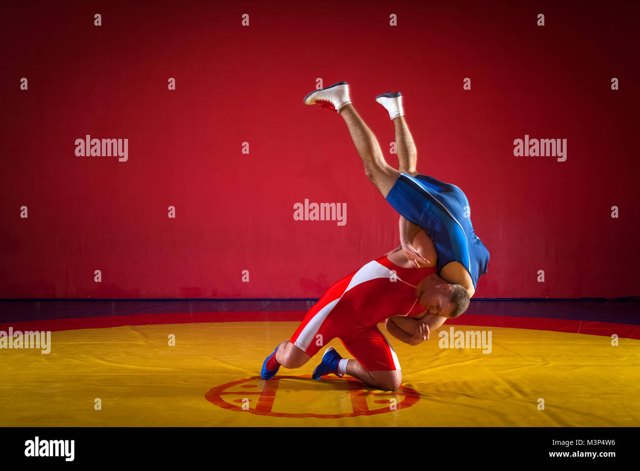 Two strong wrestlers in blue and red wrestling tights making a hip