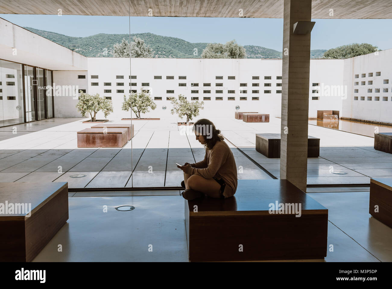 Cordoba, Spain - April 11, 2017: Madinat Al Zahara Museum designed by  Nieto Sobejano Arquitects. Visitor texting on smartphone in main hall against c Stock Photo