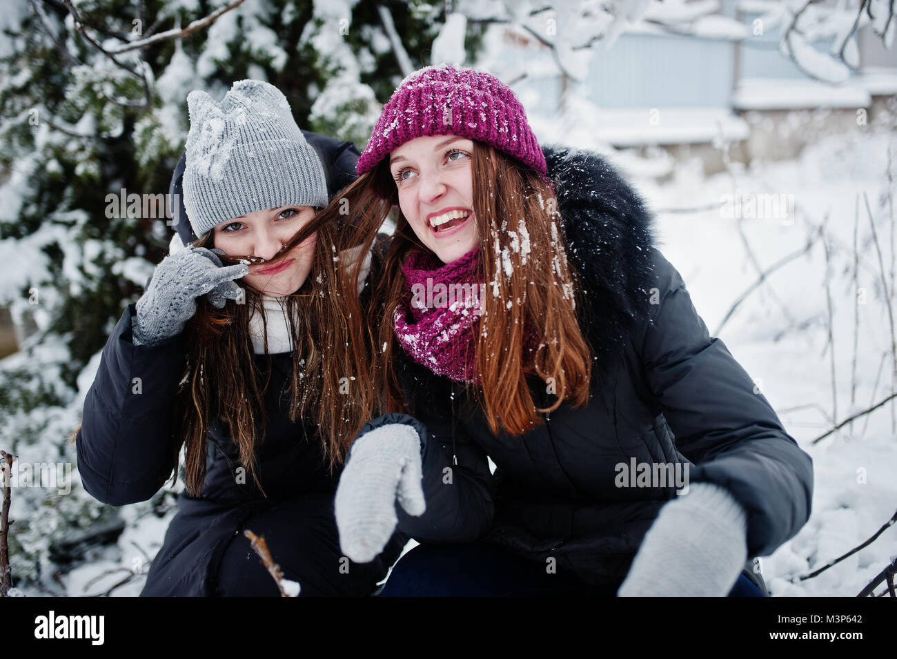 Two funny girls friends having fun at winter snowy day near snow