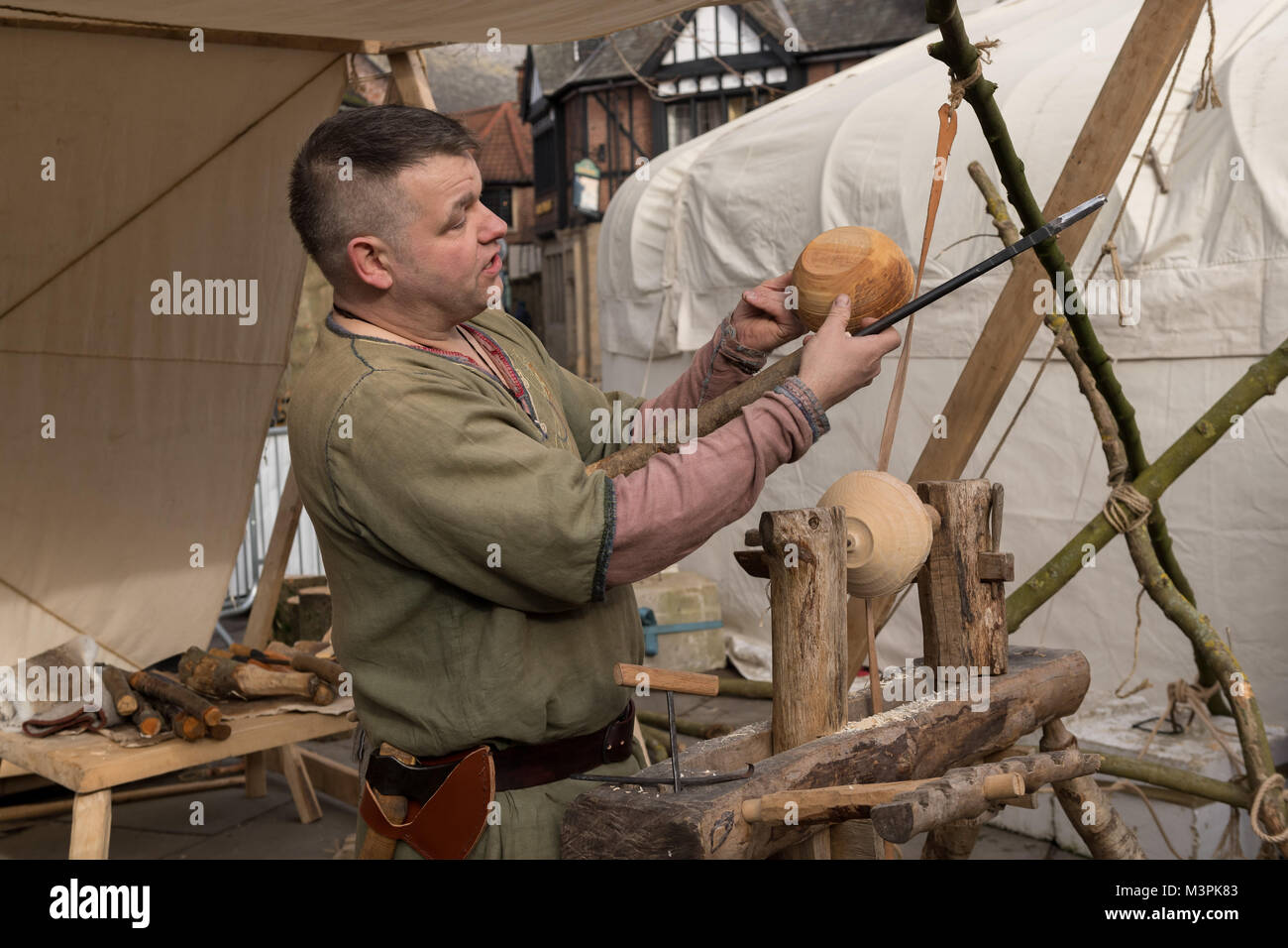 York, UK, 12th February 2018. Person dressed as a Viking at the annual Jorvik Viking Festival held in the city centre of York. This man is a skilled wood-turner & is holding & examining a wooden bowl he has just finished crafting, using a simple lathe & handmade tools. He is taking part in the realistic re-enactment of life at a Viking market. North Yorkshire, England, UK.  Credit: Ian Lamond/Alamy Live News Stock Photo