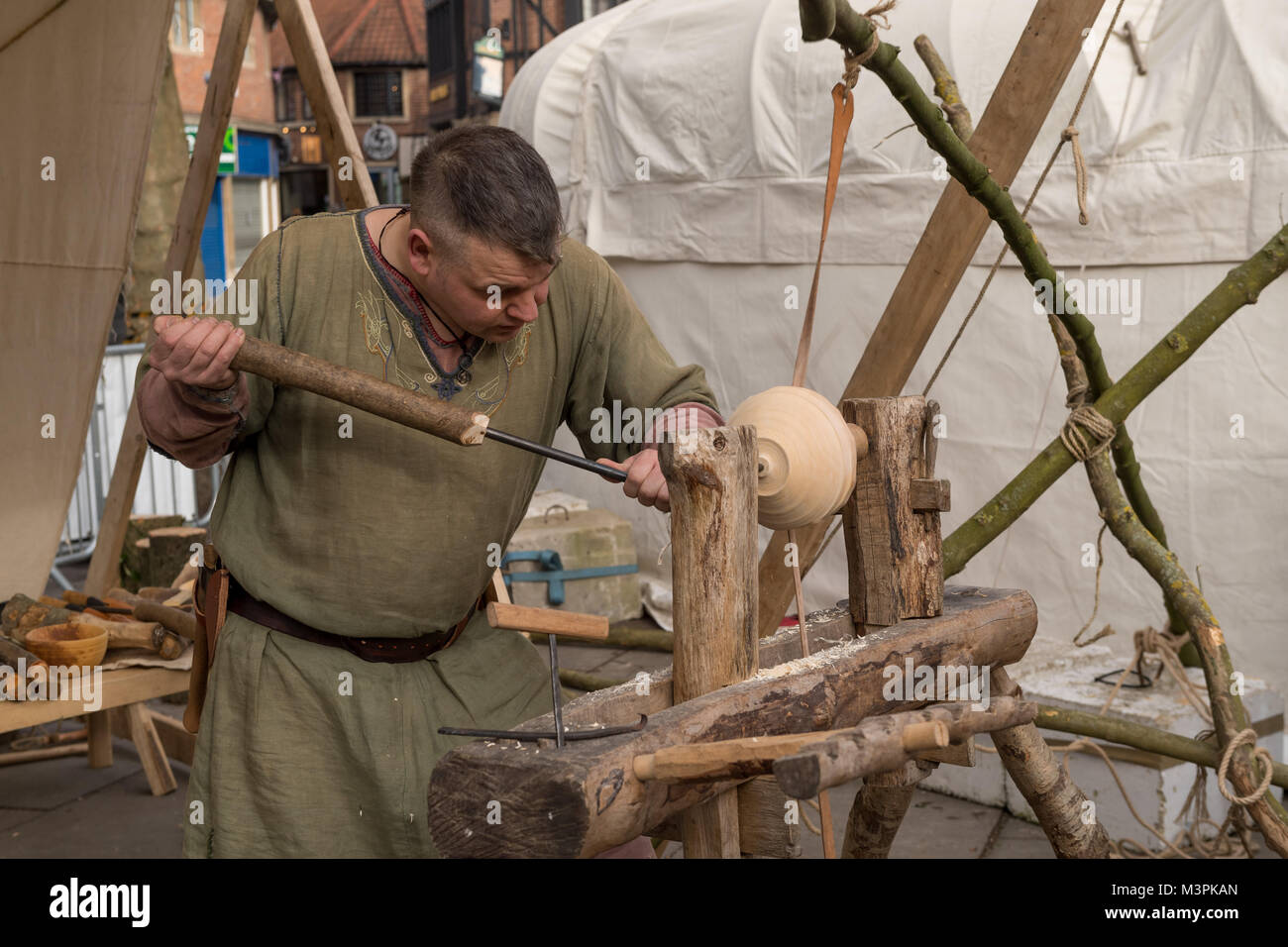 York, UK, 12th February 2018. Person dressed as a Viking at the annual Jorvik Viking Festival held in the city centre of York. This man is a skilled wood-turner & is concentrating on crafting a wooden bowl, using a simple lathe & handmade tools. He is taking part in the realistic re-enactment of life at a Viking market. North Yorkshire, England, UK. Credit: Ian Lamond/Alamy Live News Stock Photo
