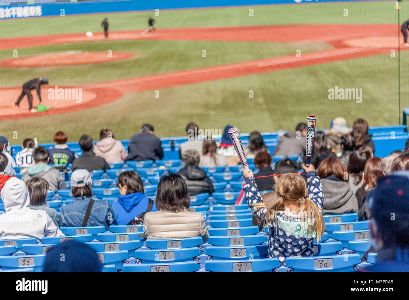 Young blonde girl cheering at Japanese baseball Stock Photo