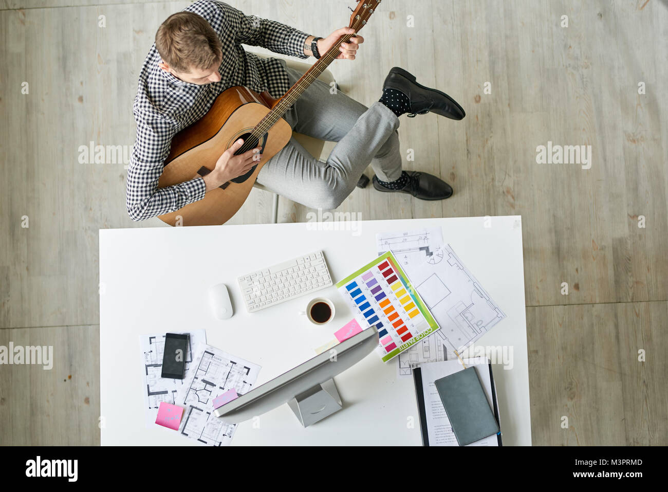 Designer Playing Guitar at Workplace Stock Photo